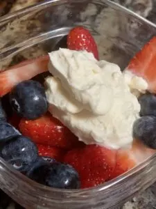 whipped cream on strawberries and blueberries